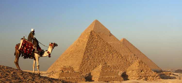 Man riding on a camel in front of pyramids | Egypt