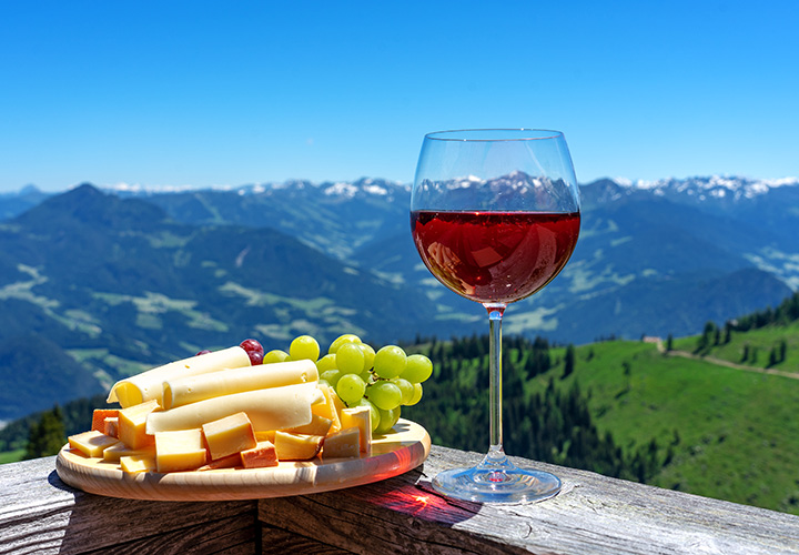 Fresh tirol cheese with wine and grapes over mountain landscape