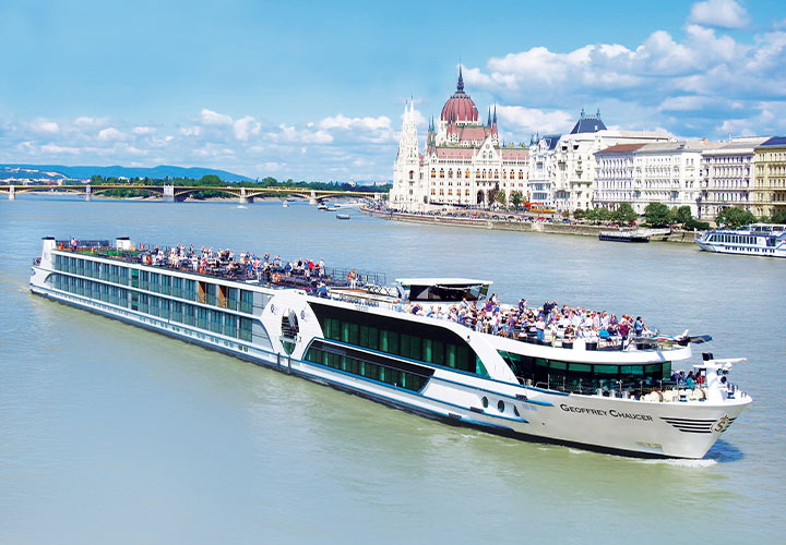 Passengers atop the MS Geoffrey Chaucer sailing in front of the Hungarian Parliament Building | Budapest, Hungary 